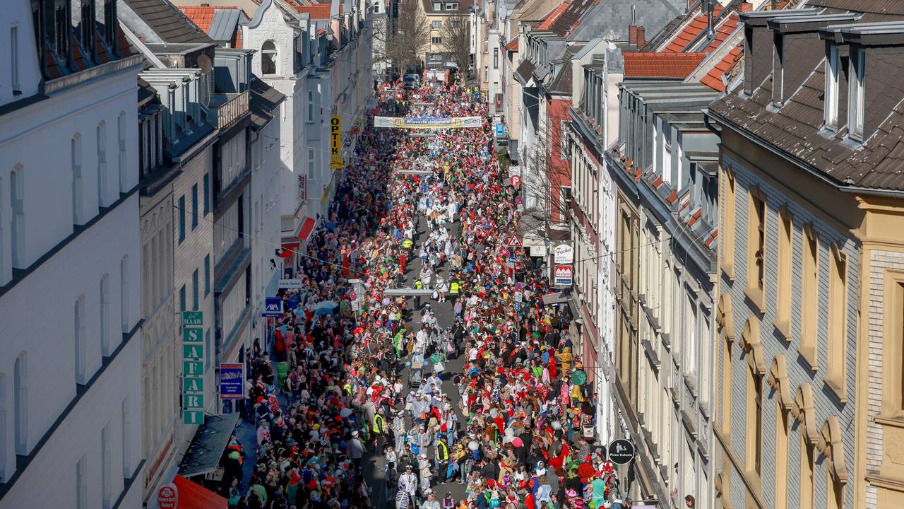 Menschen stehen an einem Karnevalsumzug am Straßenrand.