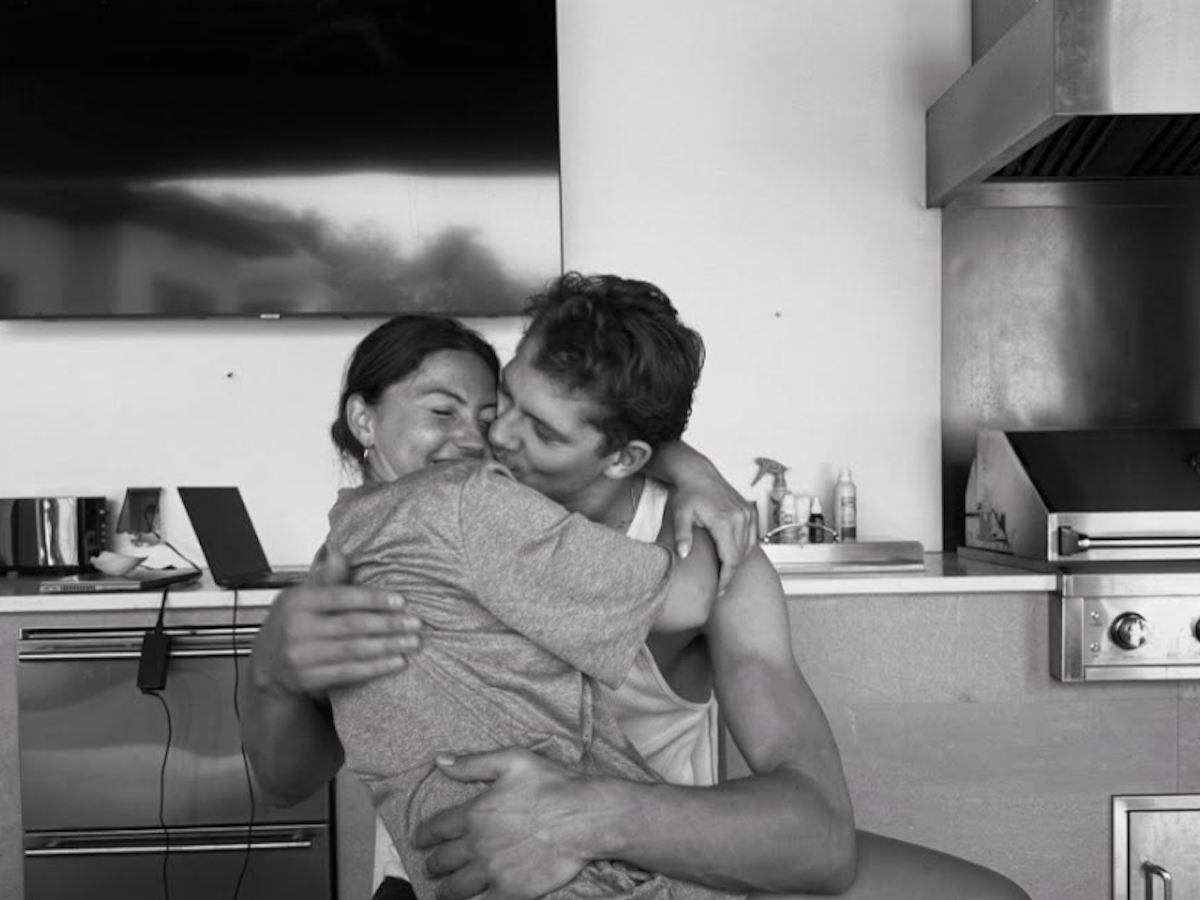 Moritz Wagner küsst seine Freundin auf die Wange, während diese auf seinem Schoß sitzt.