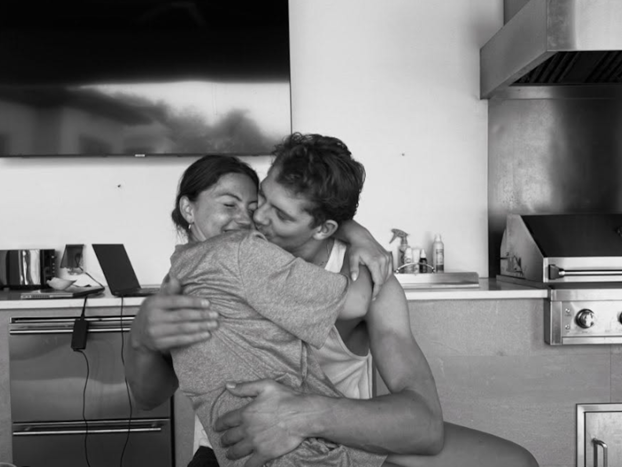 Moritz Wagner küsst seine Freundin auf die Wange, während diese auf seinem Schoß sitzt.