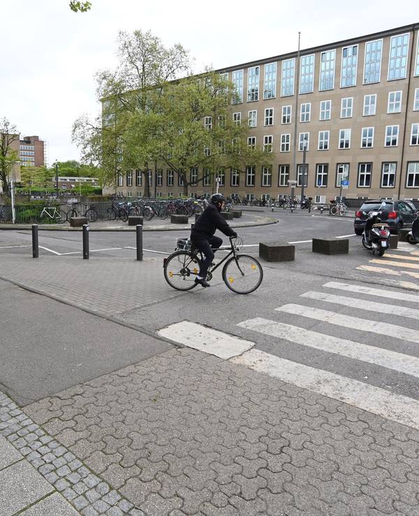 Ein Radfahrer und mehrere Autos stehen auf dem Albertus-Magnus-Platz vor der Universität zu Köln.