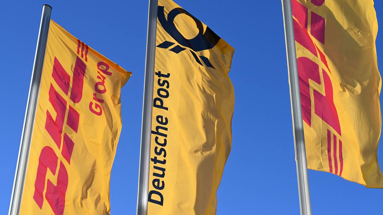 Fahnen des Logistikkonzerns DHL und seiner Brieftochter Deutsche Post (M.) wehen vor der Konzernzentrale in Bonn an Masten.