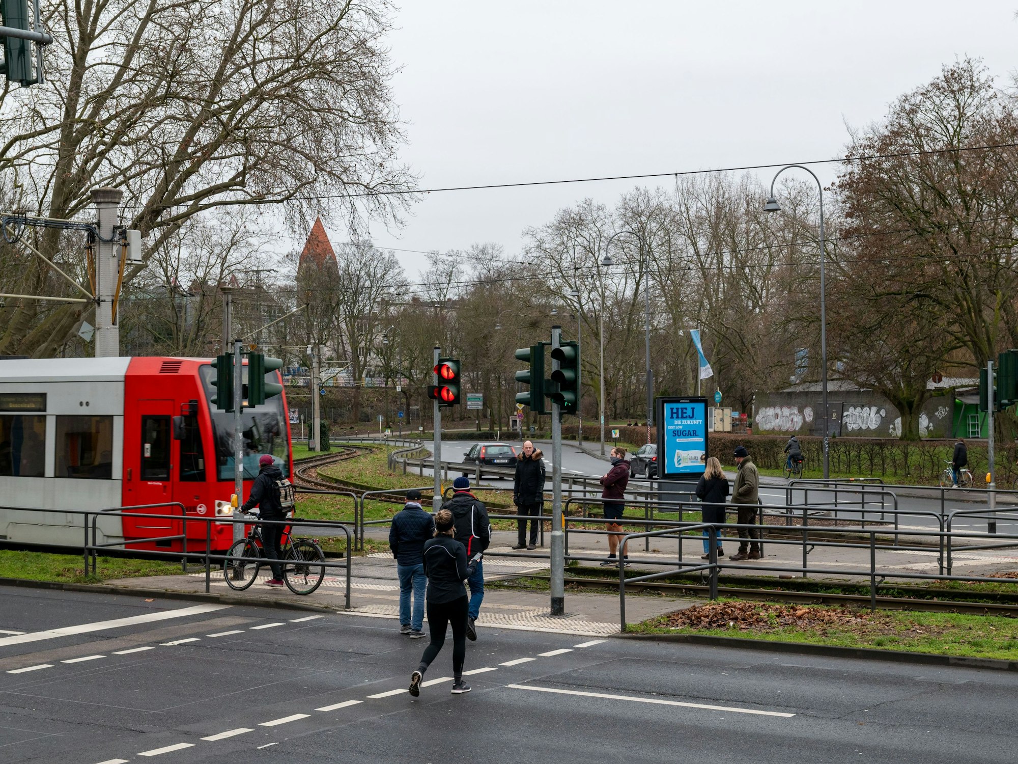 Menschen überqueren KVB-Gleise in Köln.