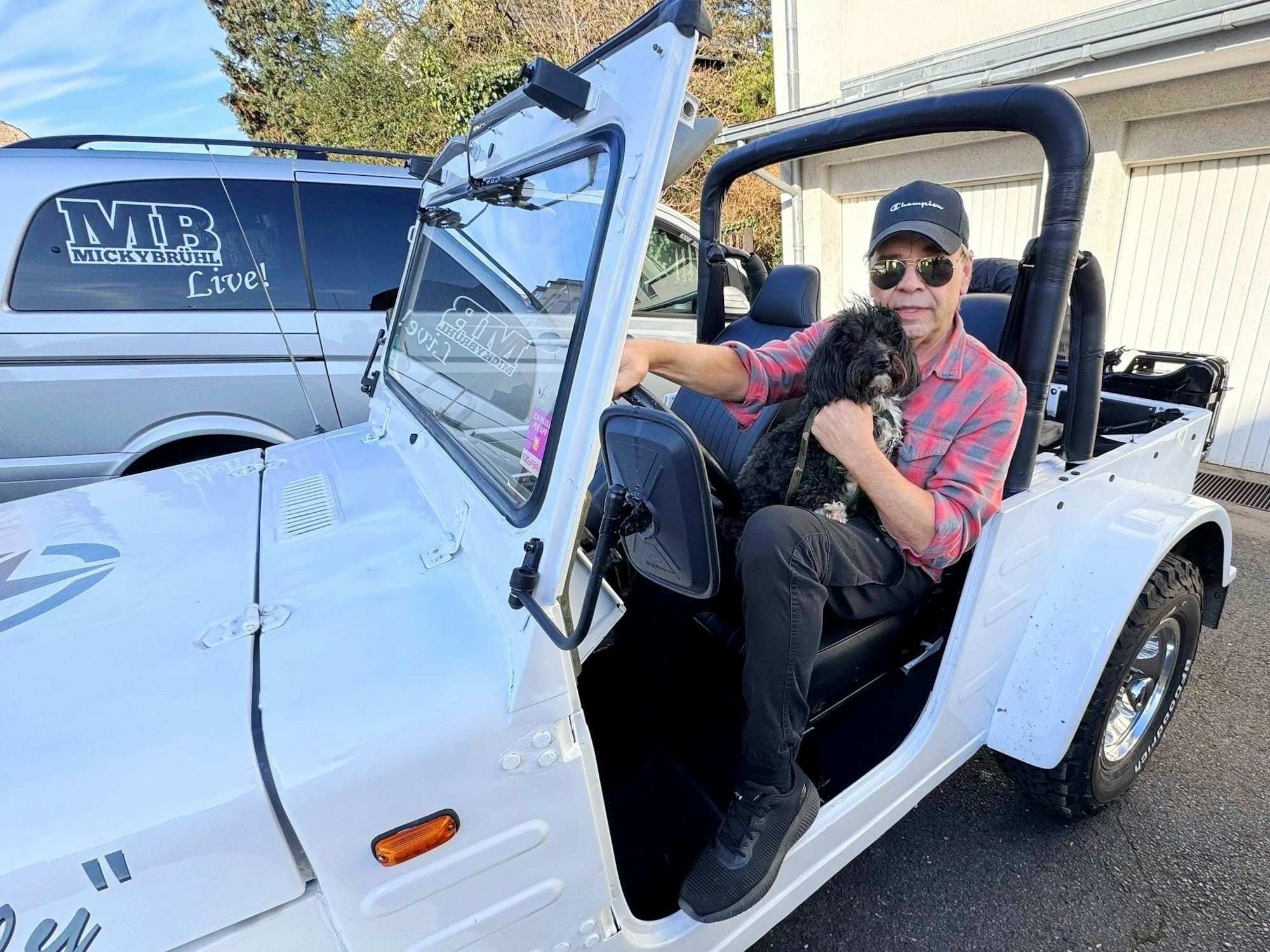 Micky Brühl in seinem Jeep mit Hund auf dem Arm.