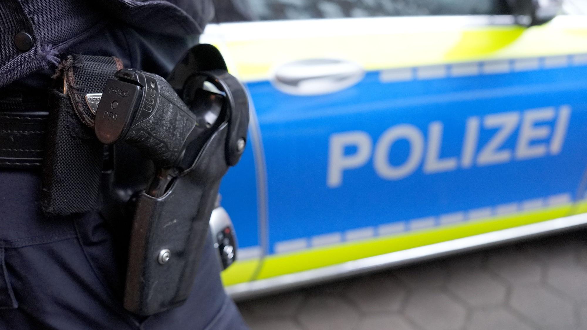 Ein Polizist steht vor einem Einsatzfahrzeug der Polizei
