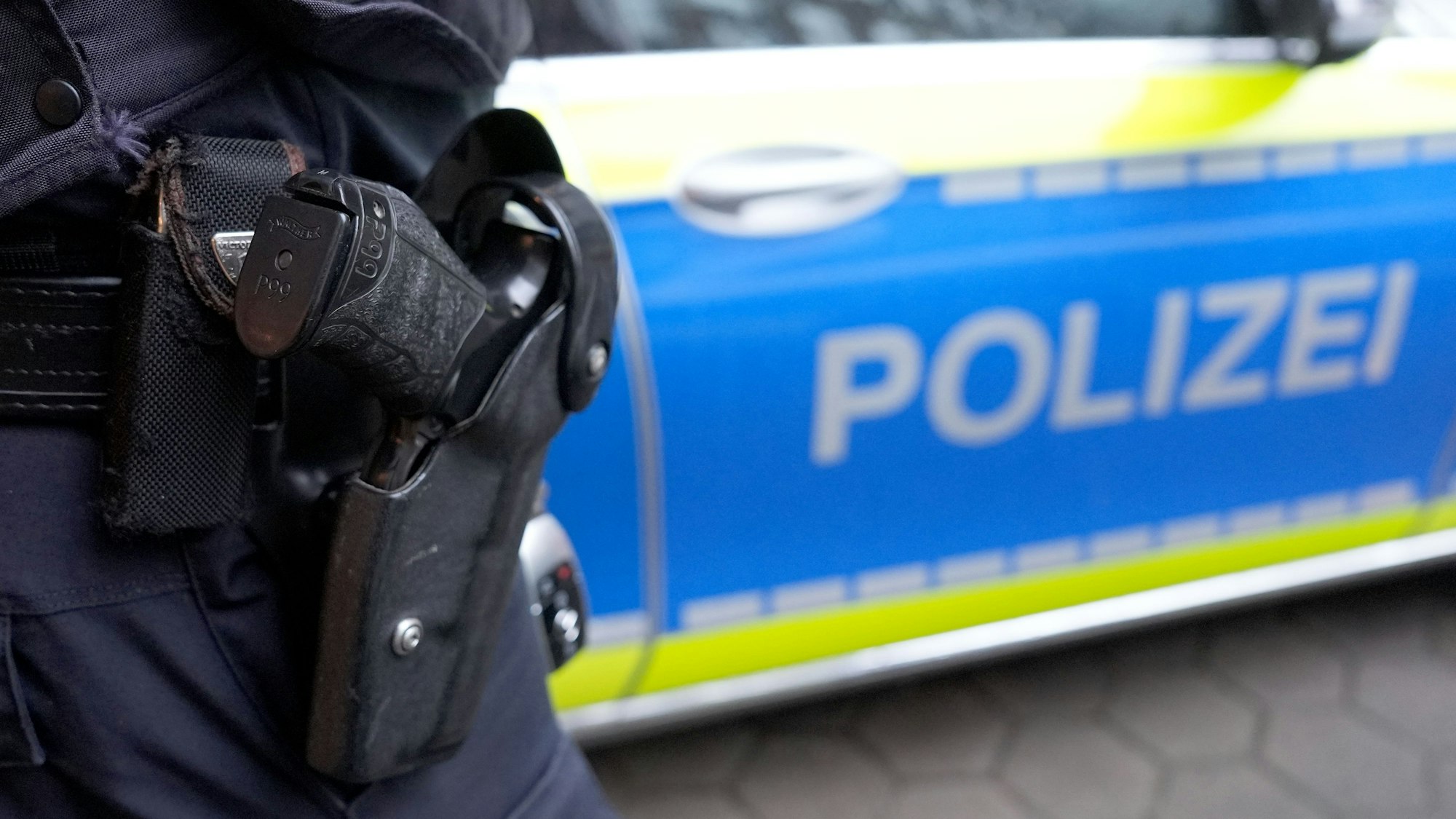 Ein Polizist steht vor einem Einsatzfahrzeug der Polizei