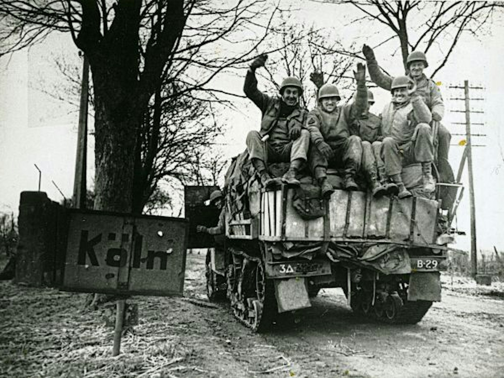 Panzer mit US-Streitkräften passiert ein Ortsschild von Köln.