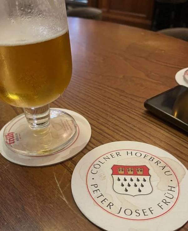 Ein Glas Kölsch und ein Bierdeckel auf einem Tisch