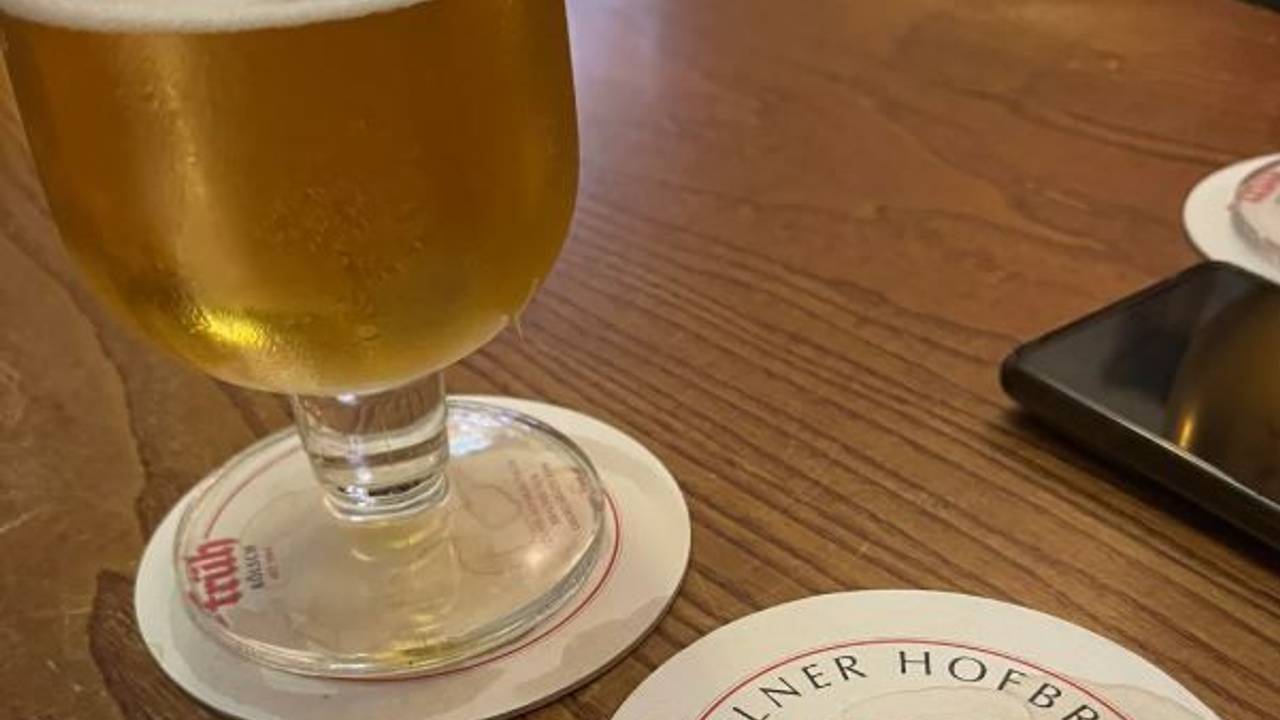 Ein Glas Kölsch und ein Bierdeckel auf einem Tisch