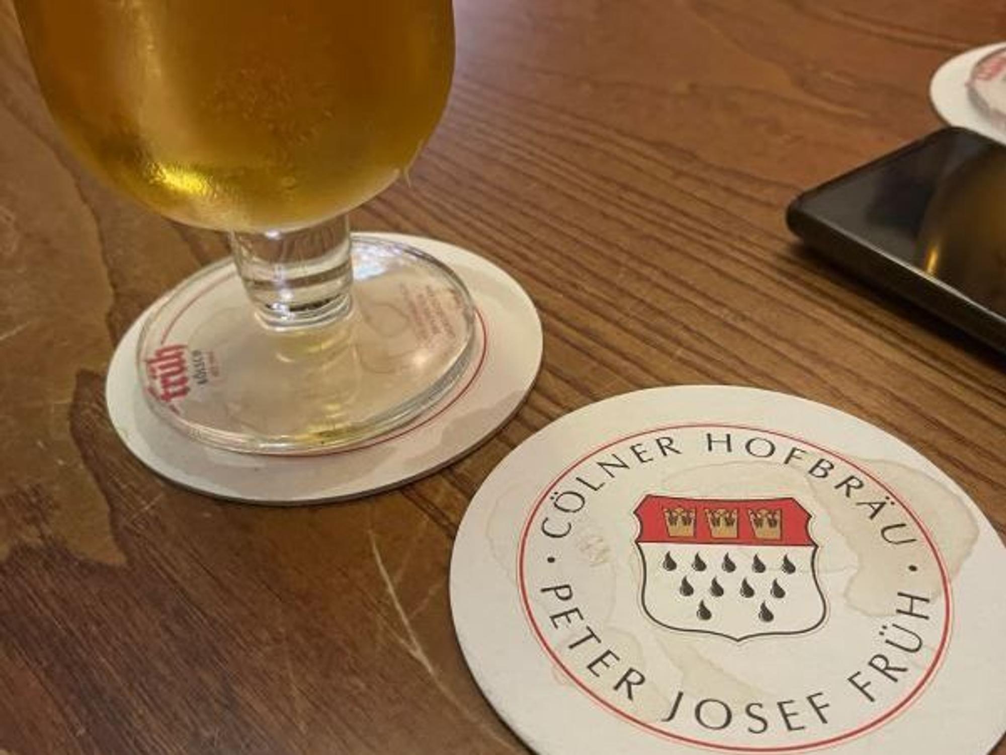 Ein Glas Kölsch und ein Bierdeckel auf einem Tisch