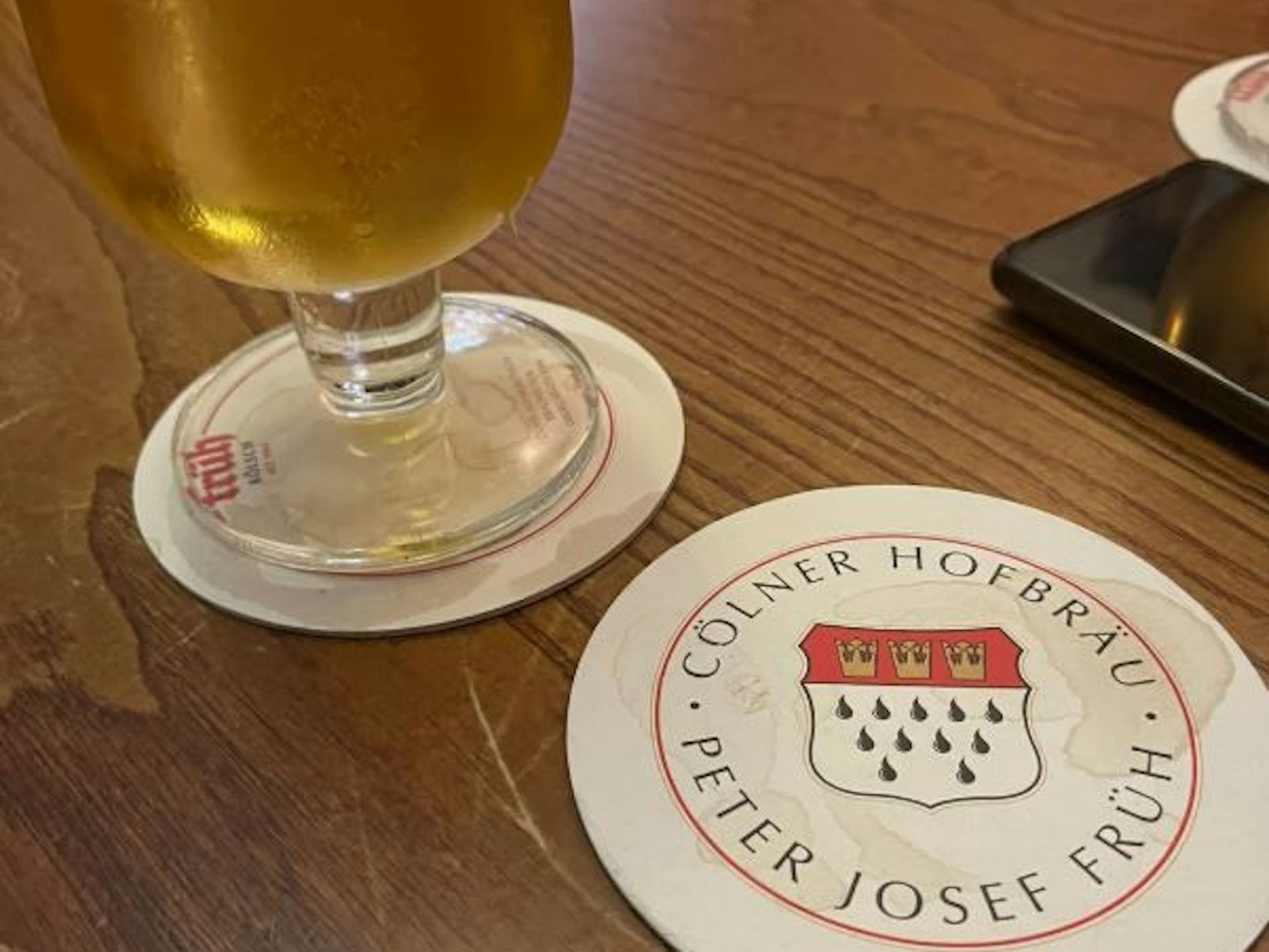 Ein Glas Kölsch und ein Bierdeckel auf einem Tisch