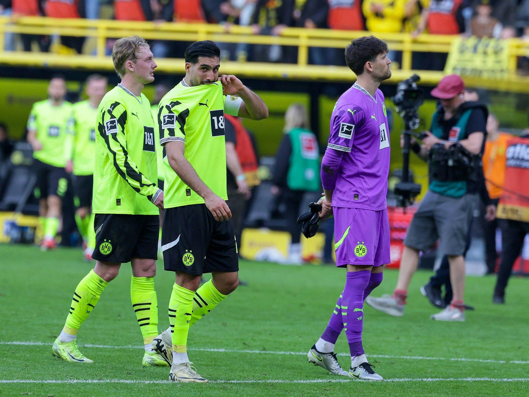 Julian Brandt, Emre Can und Gregor Kobel laufen nach der Heimpleite gegen den FC Augsburg enttäuscht über den Rasen.