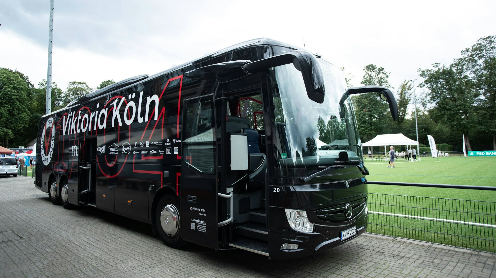Der Bus von Viktoria Köln steht vor einem Fußballplatz.