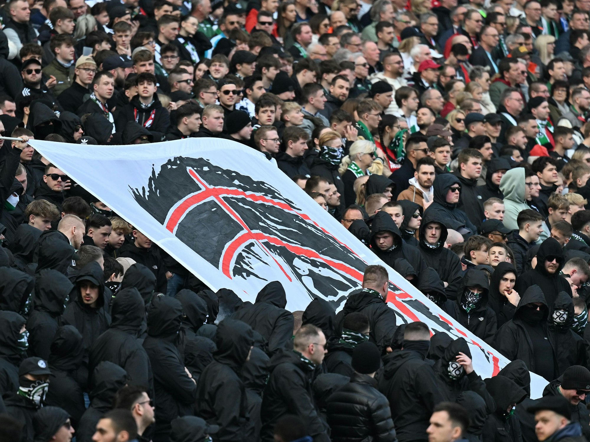 Fans halten auf der Tribüne ein Banner hoch.