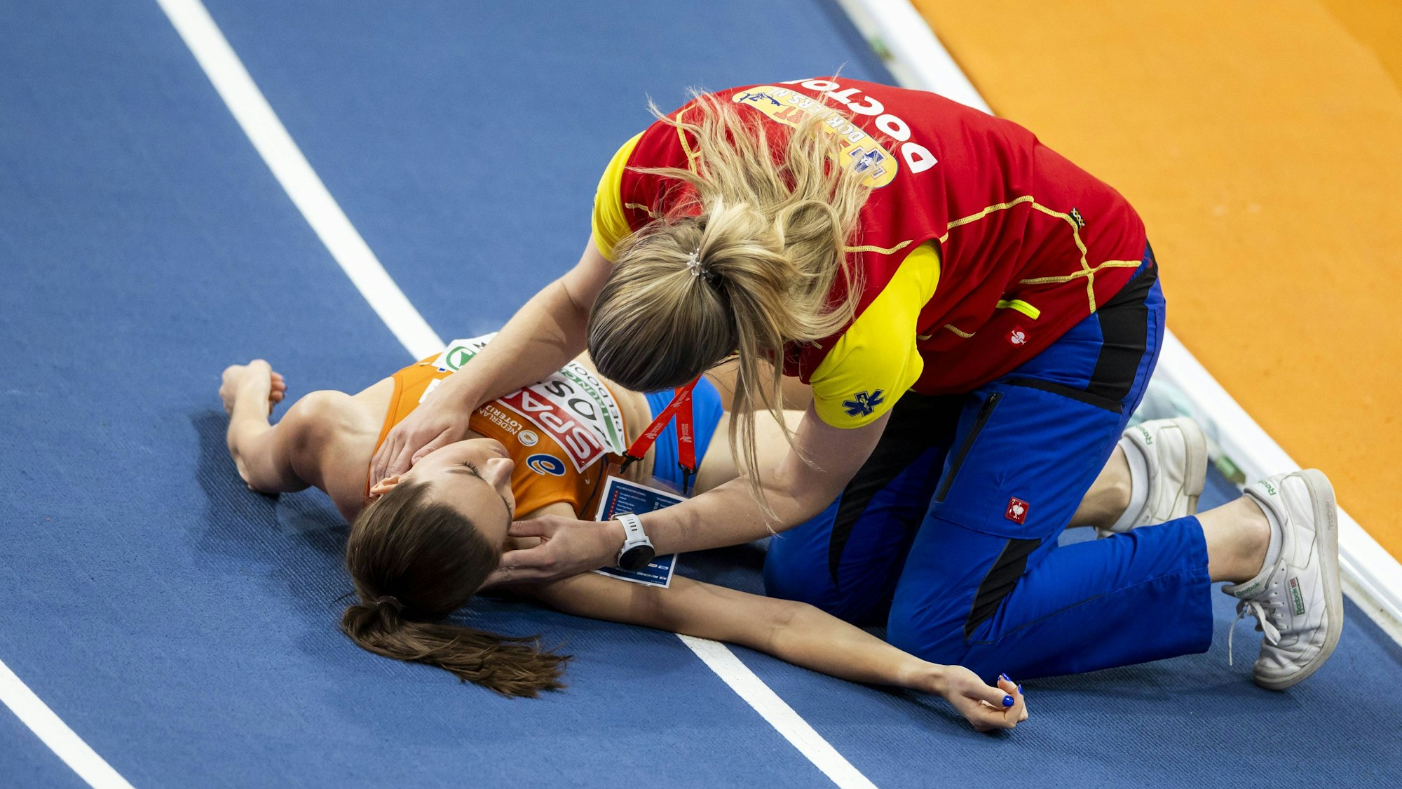 Einer Helferin kümmert sich um die bewusstlos auf der Bahn liegende Maureen Koster.