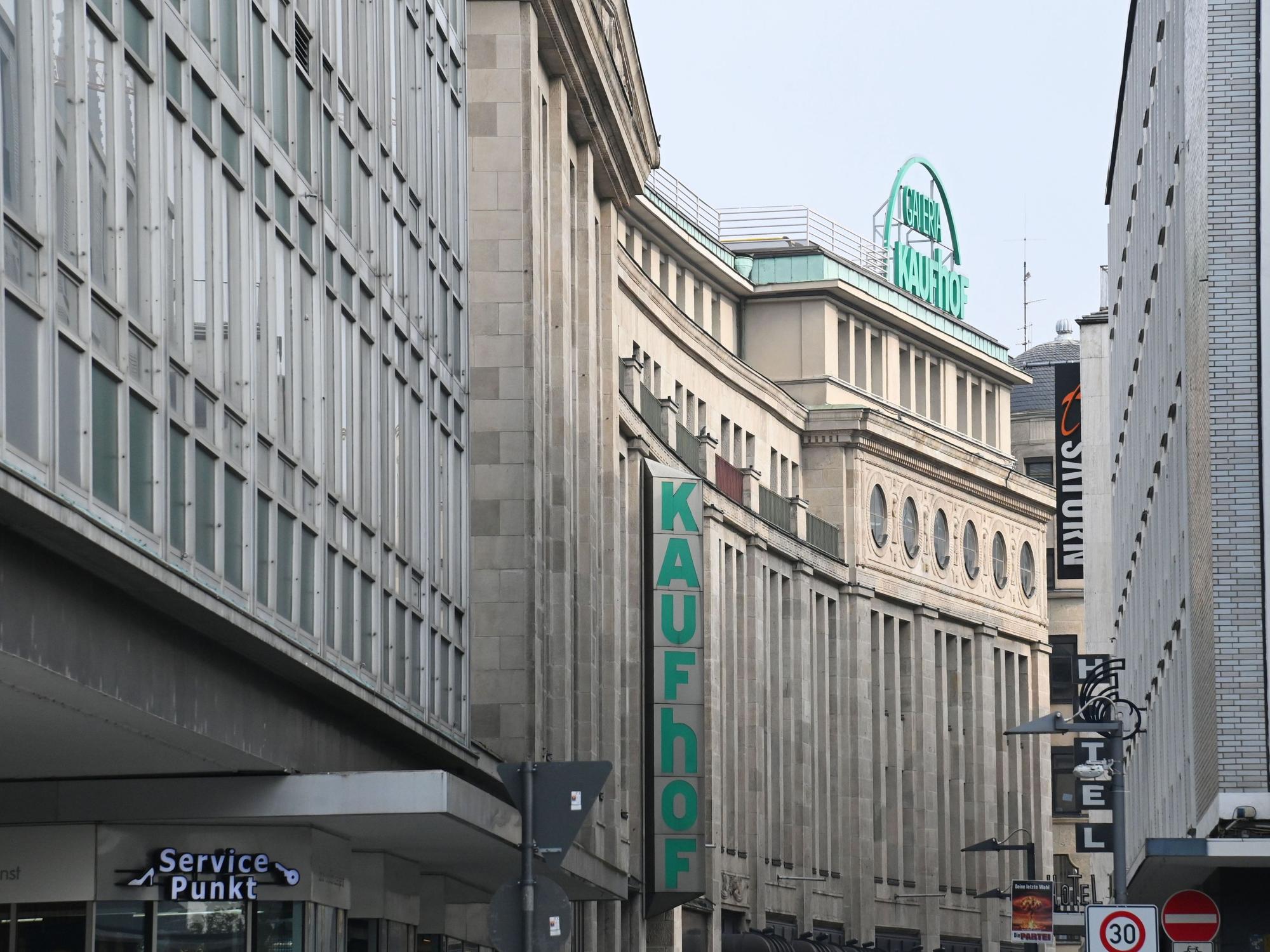 Eine Häuserreihen in der Kölner Innenstadt, an dem hinteren Gebäude hängen Schilder mit den Aufschriften Kaufhof und Galeria Kaufhof.