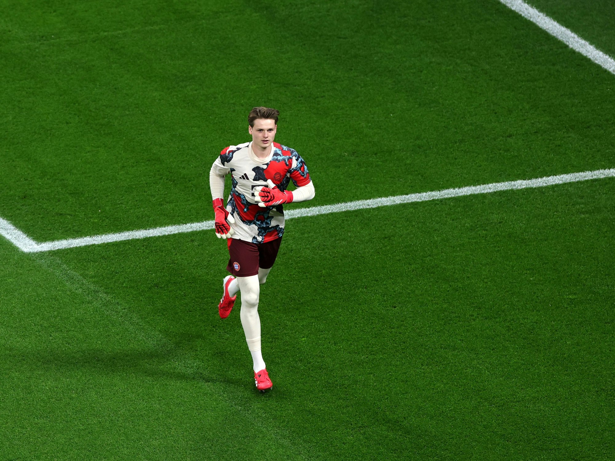 BayArena. Münchens Torhüter Jonas Urbig läuft sich vor dem Spiel warm.