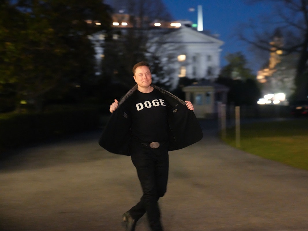 Elon Musk zeigt den Medien sein T-Shirt mit der Aufschrift „DOG“E, während er auf dem Südrasen des Weißen Hauses in Washington geht.