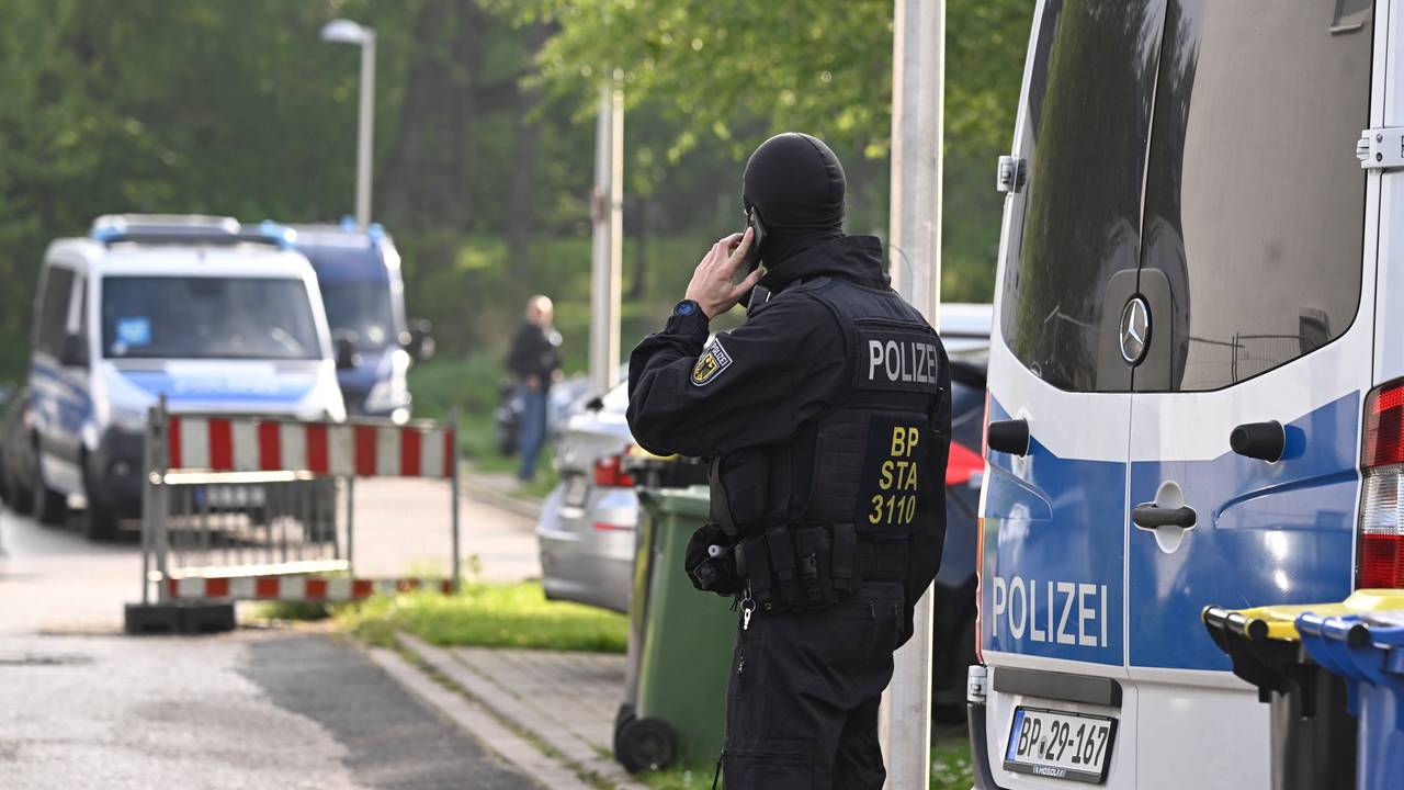 Ein Bundespolizist steht während einer Razzia auf der Straße und telefoniert.