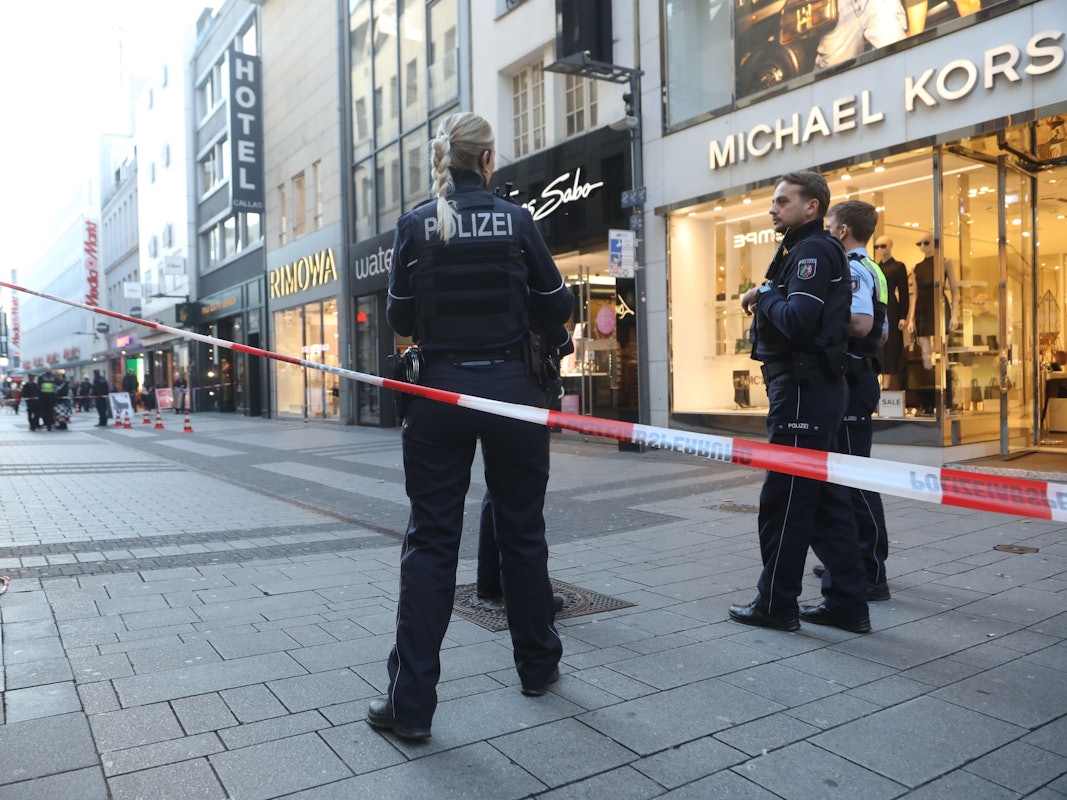 Die Polizei hat eine Fußgängerzone abgesperrt, am Flatterband stehen drei Einsatzkräfte.