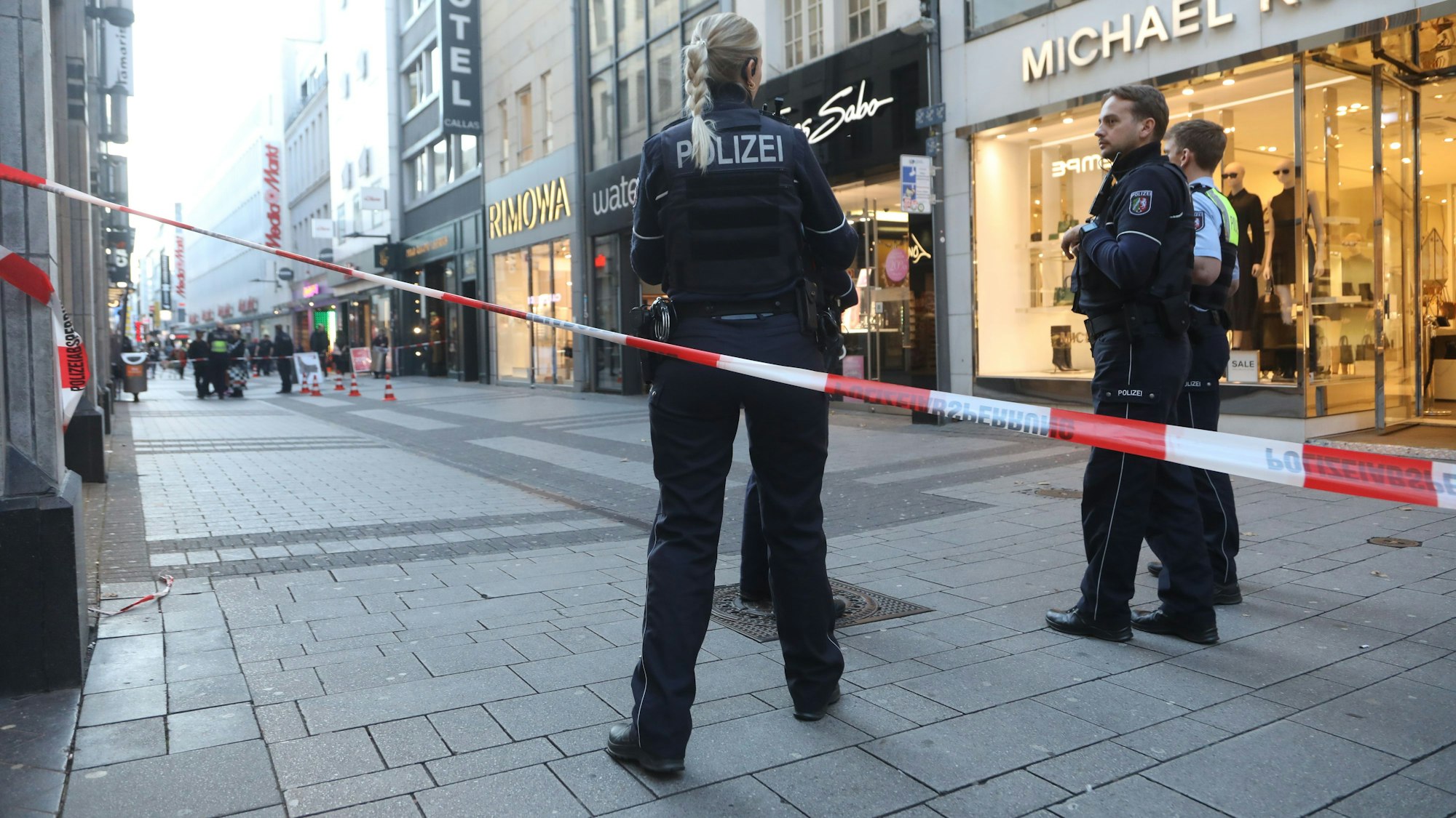 Die Polizei hat eine Fußgängerzone abgesperrt, am Flatterband stehen drei Einsatzkräfte.