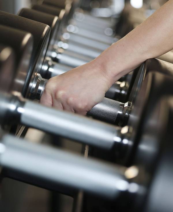 Eine Person greift Hanteln in einem Fitnessstudio.