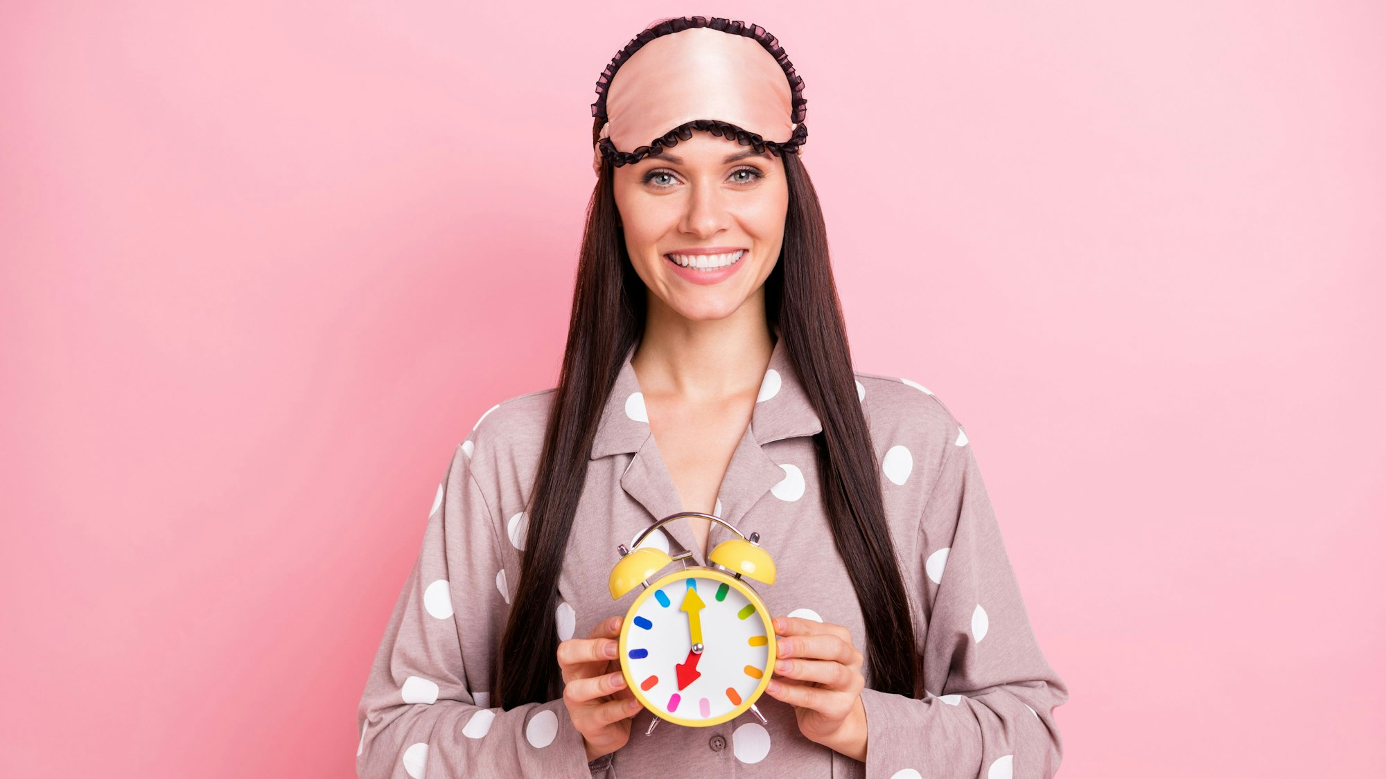 Frau hält Wecker mit Uhrzeit 7 Uhr in der Hand