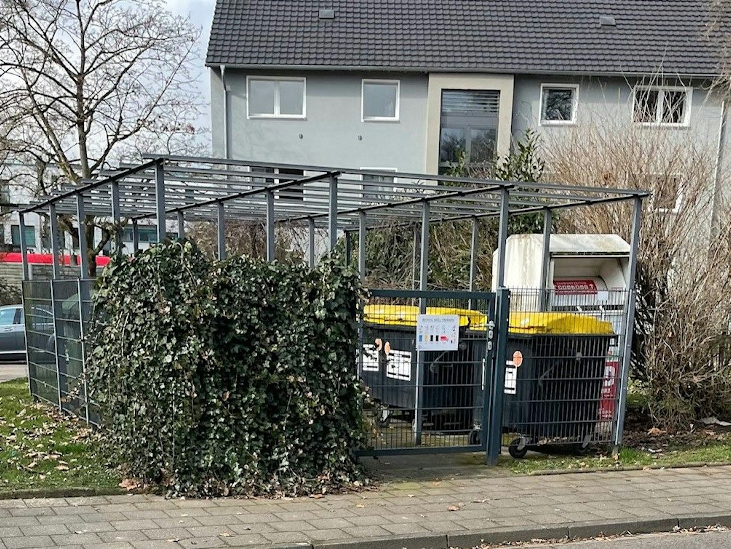 Müllcontainer stehen hinter einem Zaun