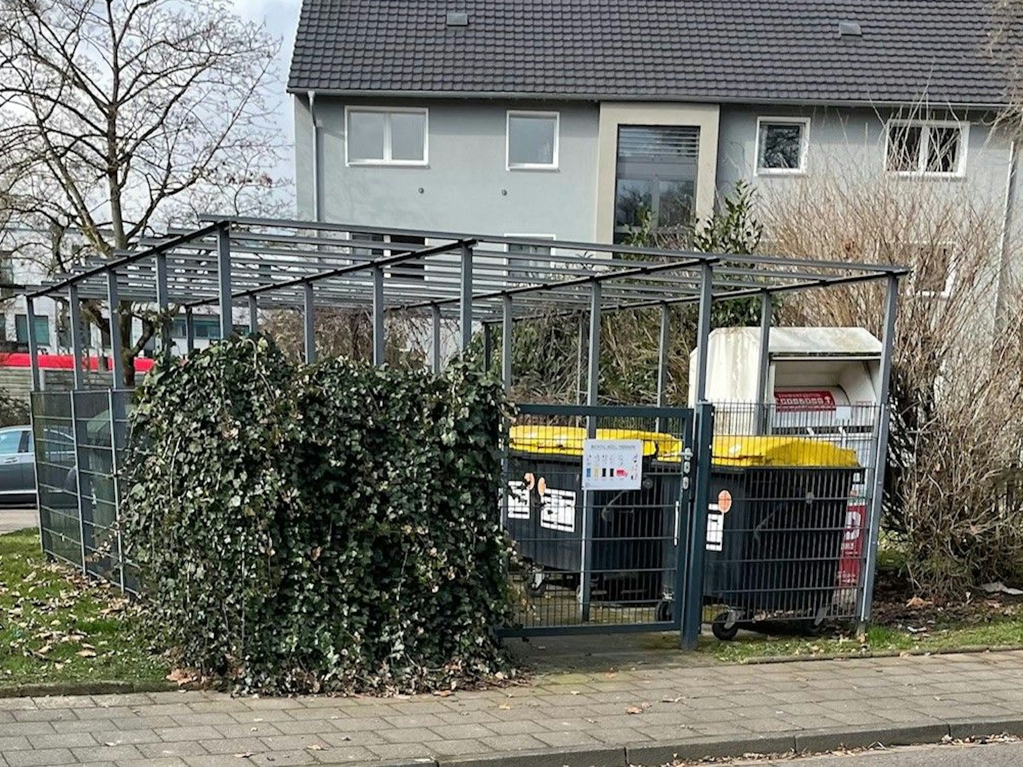 Müllcontainer stehen hinter einem Zaun