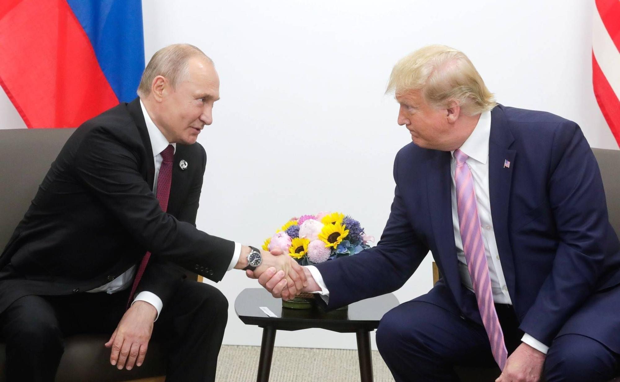 Donald Trump schüttelt die Hand von Wladimir Putin.