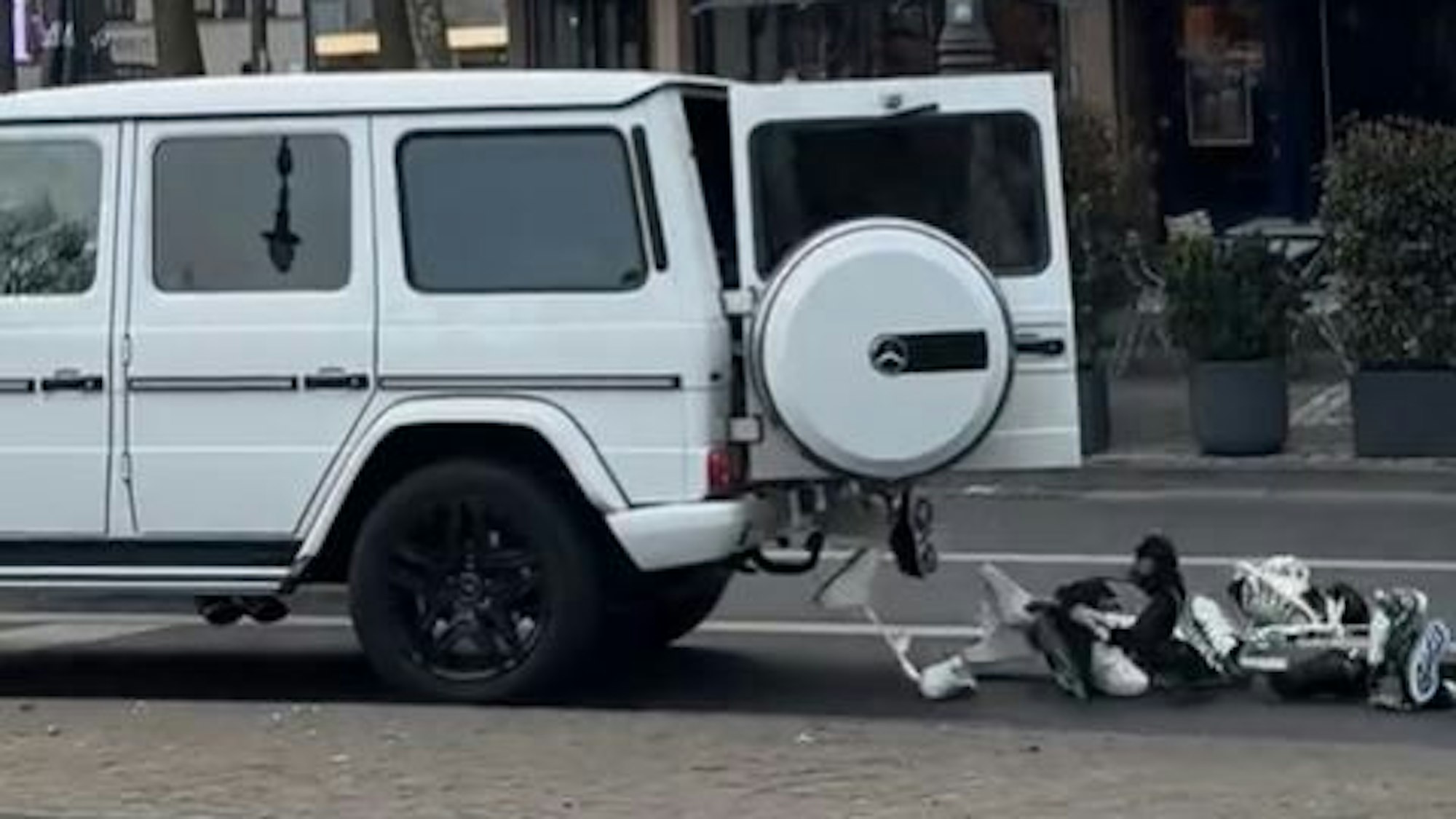 Ein weißer Mercedes fährt über die Kölner Ringe – plötzlich geht die Hecktür auf.