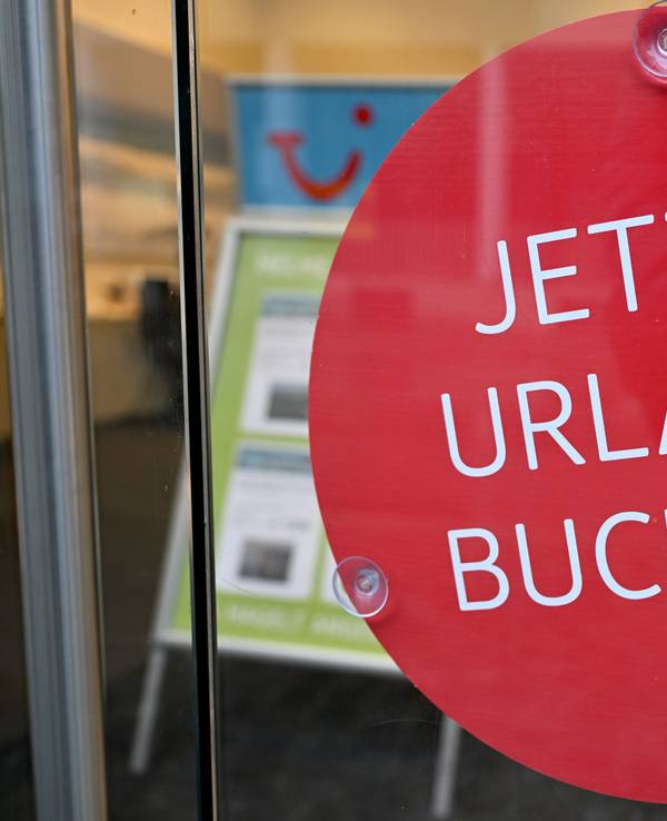 Ein Schild mit der Aufschrift „Jetzt Urlaub buchen!“ hängt in einem Reisebüro in der Münchener Innenstadt. Wer clever bucht, kann bares Geld sparen.
