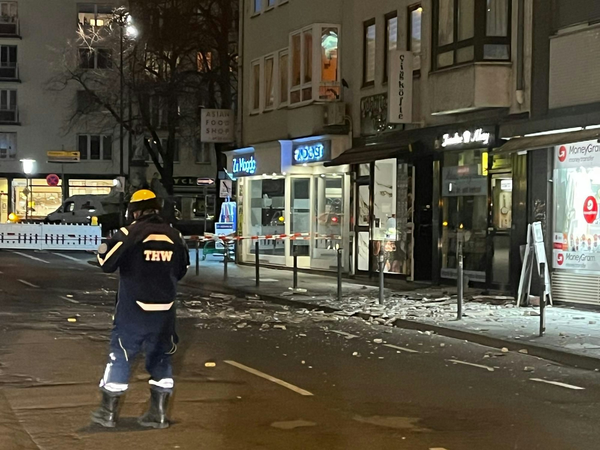 Auf einem Gehweg liegen Trümmer, der Bereich ist abgesperrt.