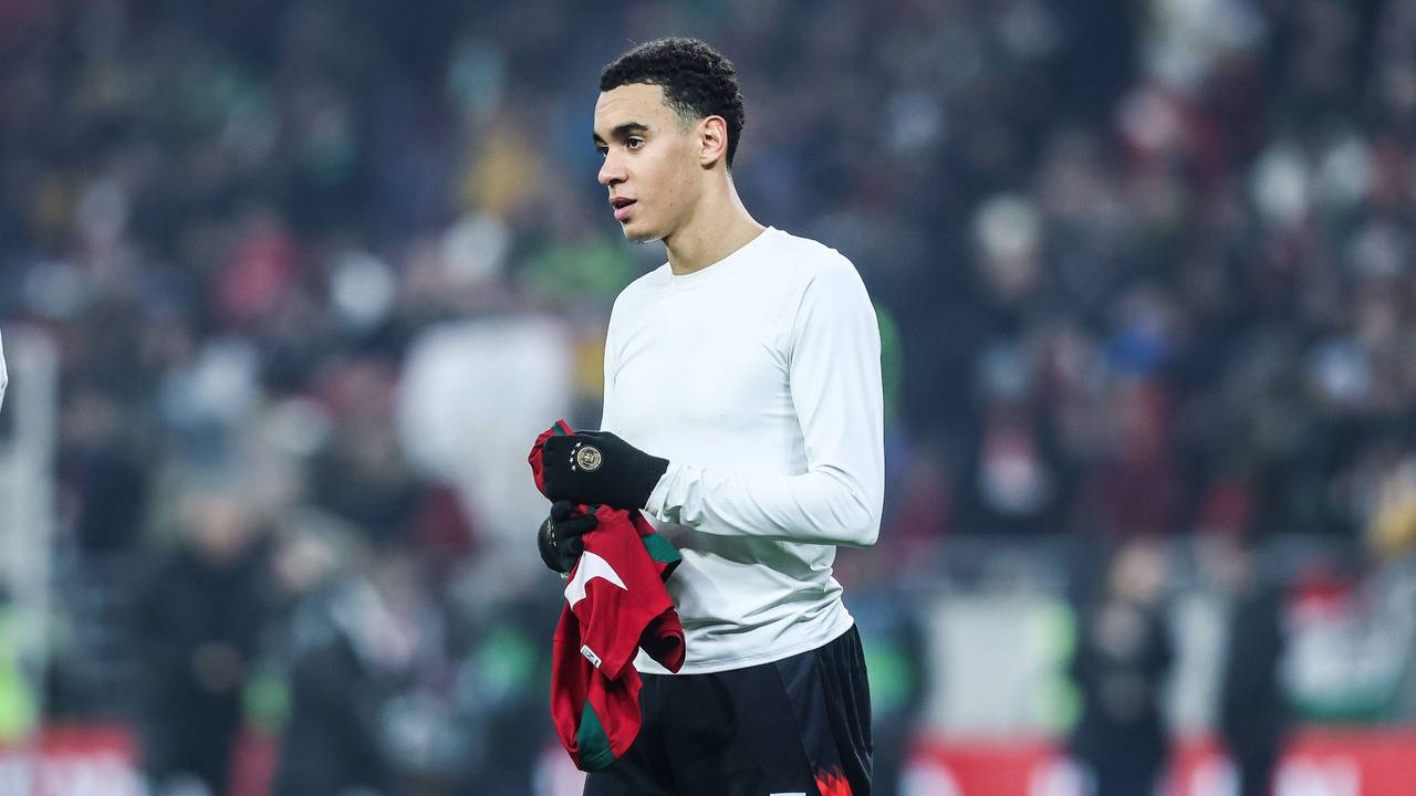 Jamal Musiala hält nach dem Trikottausch ein Shirt in den Händen.