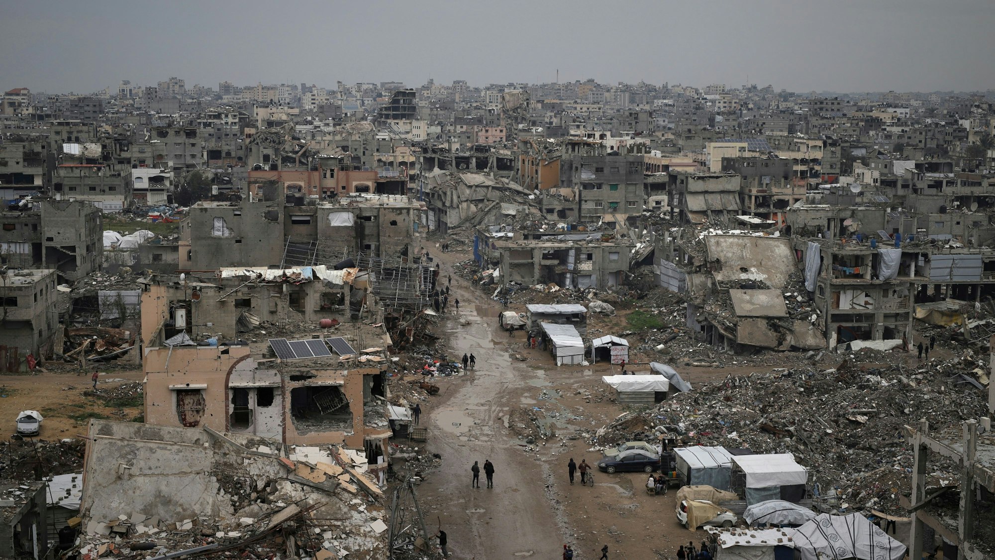 Palästinenser gehen durch die Trümmer zerstörter Häuser und Gebäude in Gaza-Stadt.