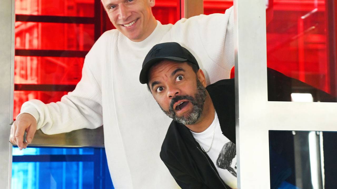 Bastian Campmann und Simon Pearce albern in einer Telefonzelle herum.
