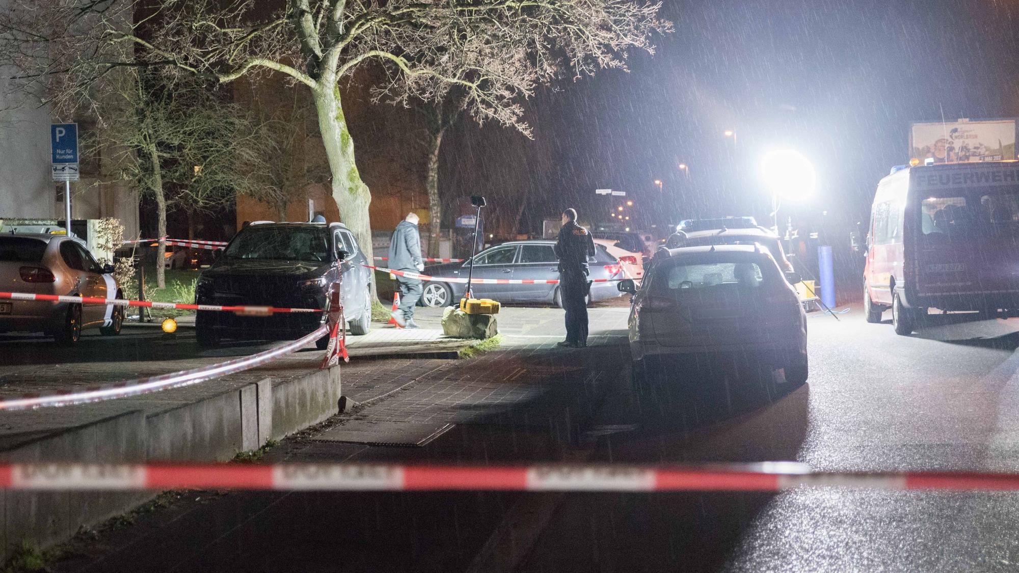 Polizei und Feuerwehr arbeiten an einem Tatort, die Straße ist abgesperrt.