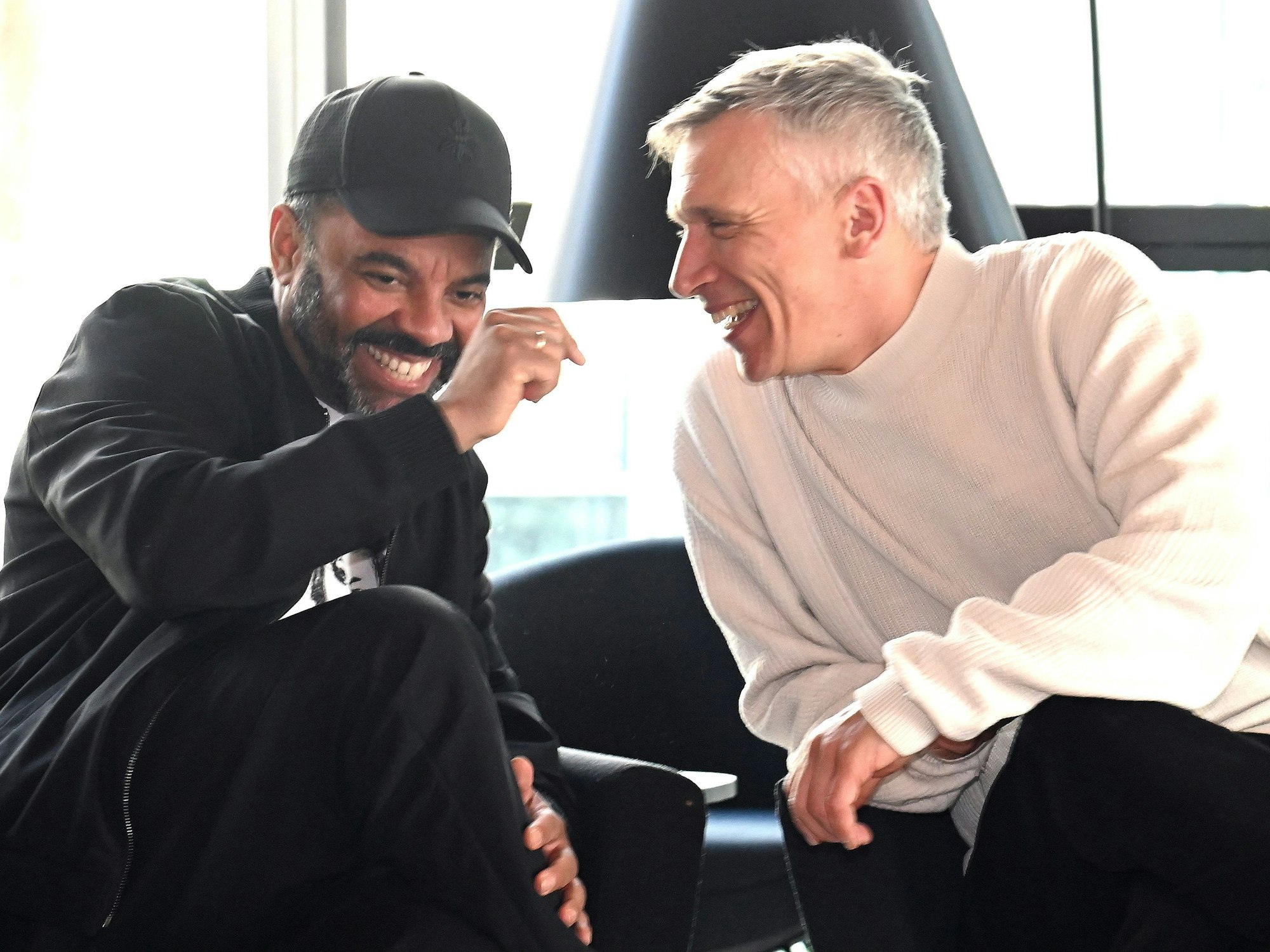 Bastian Campmann und Simon Pearce sitzen auf Stühlen nebeneinander.