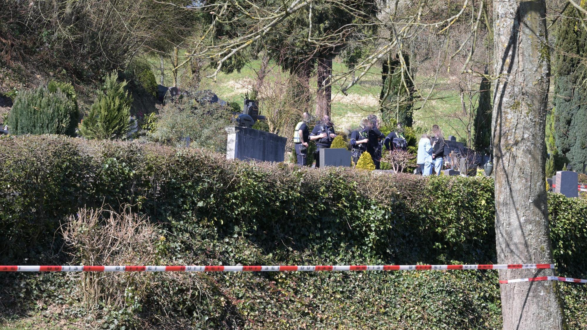 Die Polizei hat einen Friedhof abgesperrt, zwischen den Gräbern sind Polizeikräfte im Einsatz.