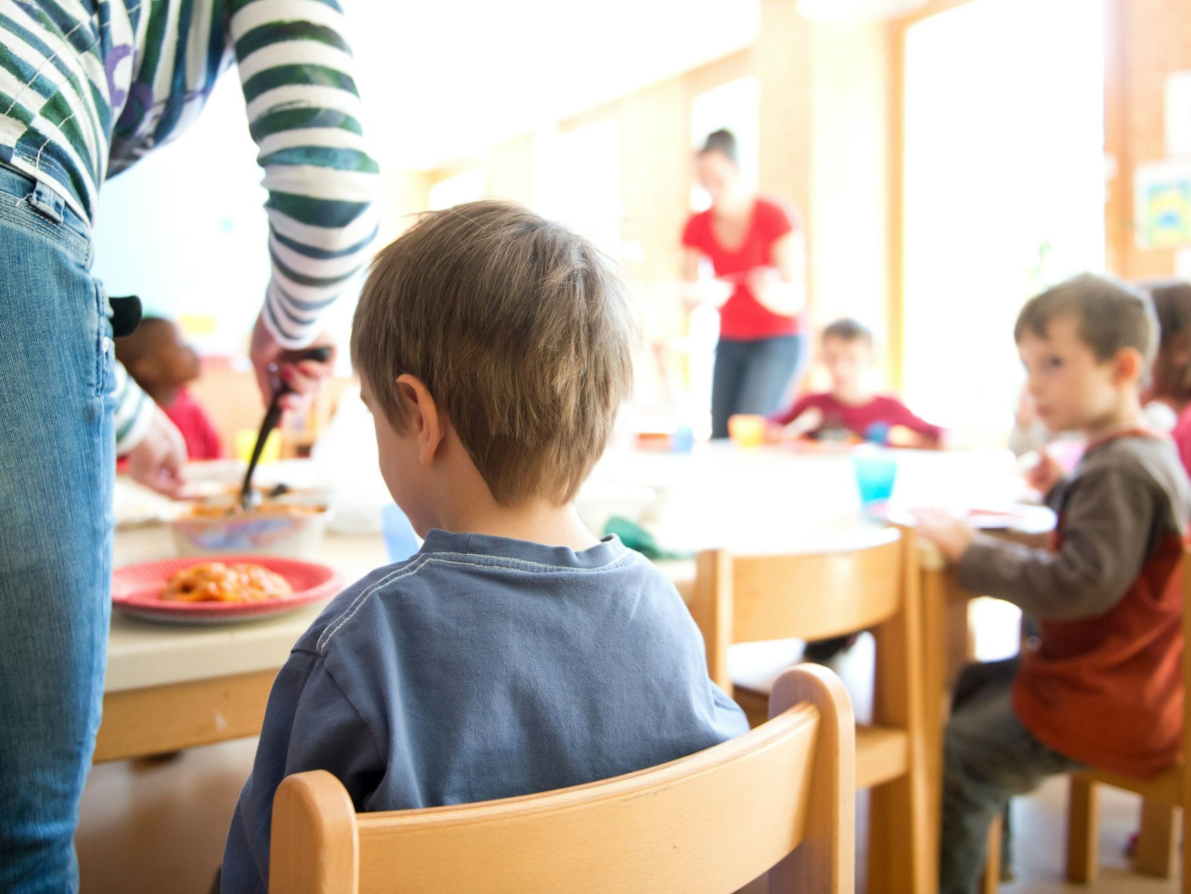 Eine Frau serviert Kindern Lasagne zum Mittagessen.