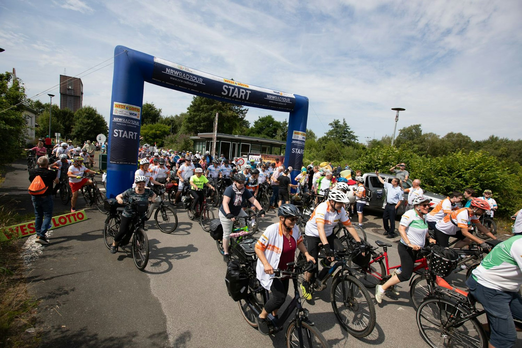 Die NRW-Radtour 2025 startet am 17. Juli in Leverkusen. Gemeinsam wird auf rund 220 Kilometer über die Etappenziele Köln – mit einer Doppelübernachtung – und Neuss zum Ausgangspunkt zurück nach Leverkusen geradelt. Anmeldungen für das vier Tage Event sind in allen WestLotto-Annahmestellen oder unter www.nrw-radtour.de möglich.
