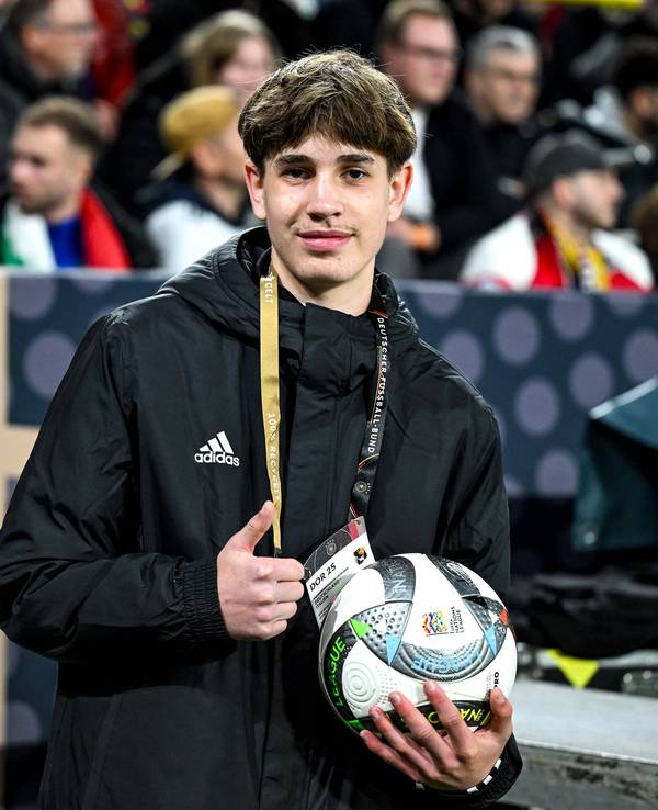 Der Balljunge, der Joshua Kimmich den Ball vor dem Eckball schnell zugeworfen hatte, lächelt in die Kamera und zeigt mit dem Daumen nach oben.