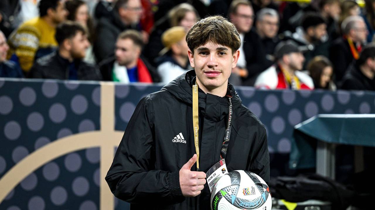 Der Balljunge, der Joshua Kimmich den Ball vor dem Eckball schnell zugeworfen hatte, lächelt in die Kamera und zeigt mit dem Daumen nach oben.