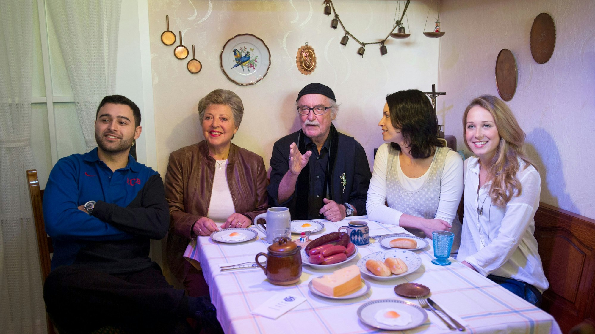Die Schauspieler Hüseyin Ekici (Orkan Kortuglu, v.l.), Marie-Luise Marjan (Helga Beimer), der Produzent der Fernsehserie „Lindenstraße“, Hans W. Geißendörfer, und die Schauspielerinnen Daniela Bette (Angelina Buchstab) und Clara Dolny (Josi Stadler) sitzen im Museum Wilhelmsbau am Technik Museum in der Originalkulisse der Wohnküche der „Lindenstraße“-Hausmeisterin Else Kling.
