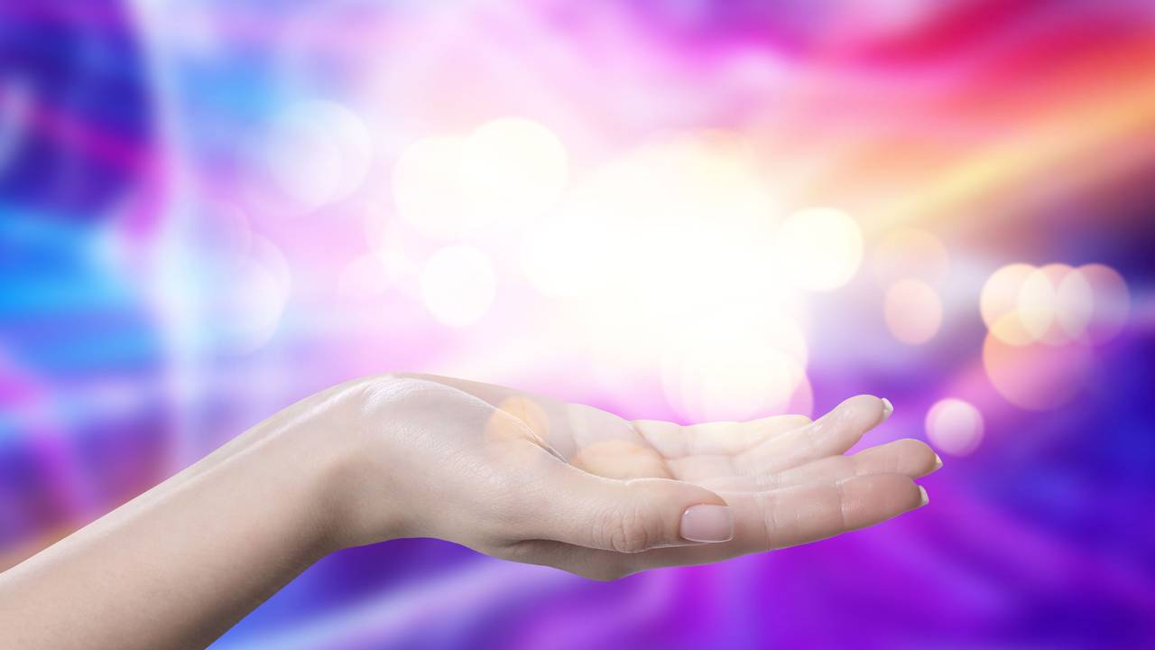 Aura phenomena. Woman with lights of energy coming out from her hand against color background, closeup