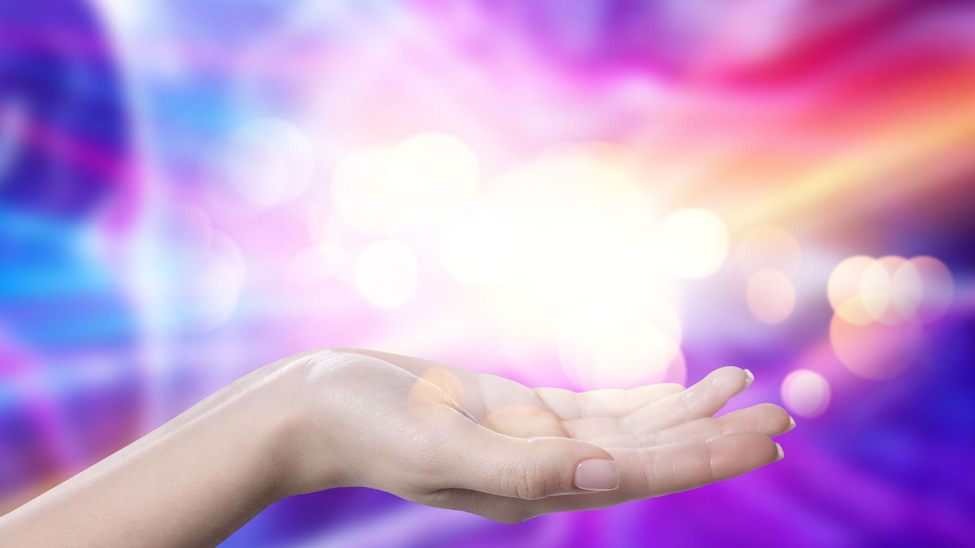 Aura phenomena. Woman with lights of energy coming out from her hand against color background, closeup