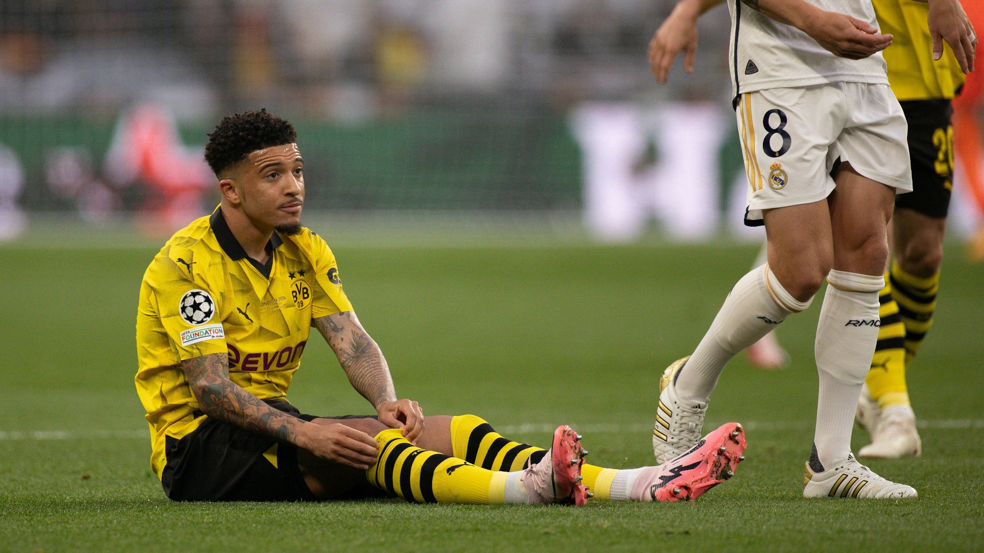 Jadon Sancho sitzt im Finale der Champions League auf dem Rasen.