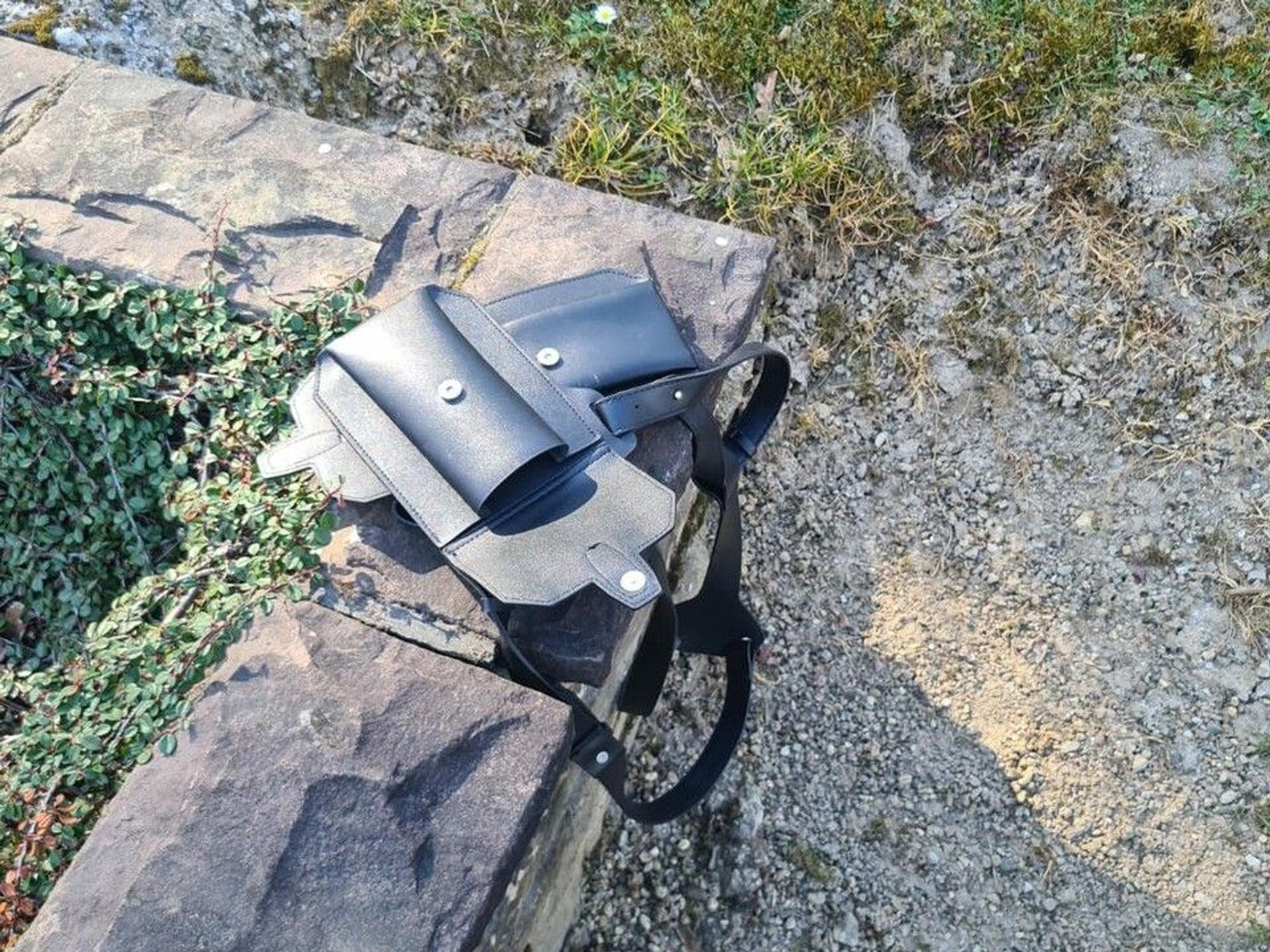 Ein Holster liegt auf der steinernen Umrandung eines Grabes.