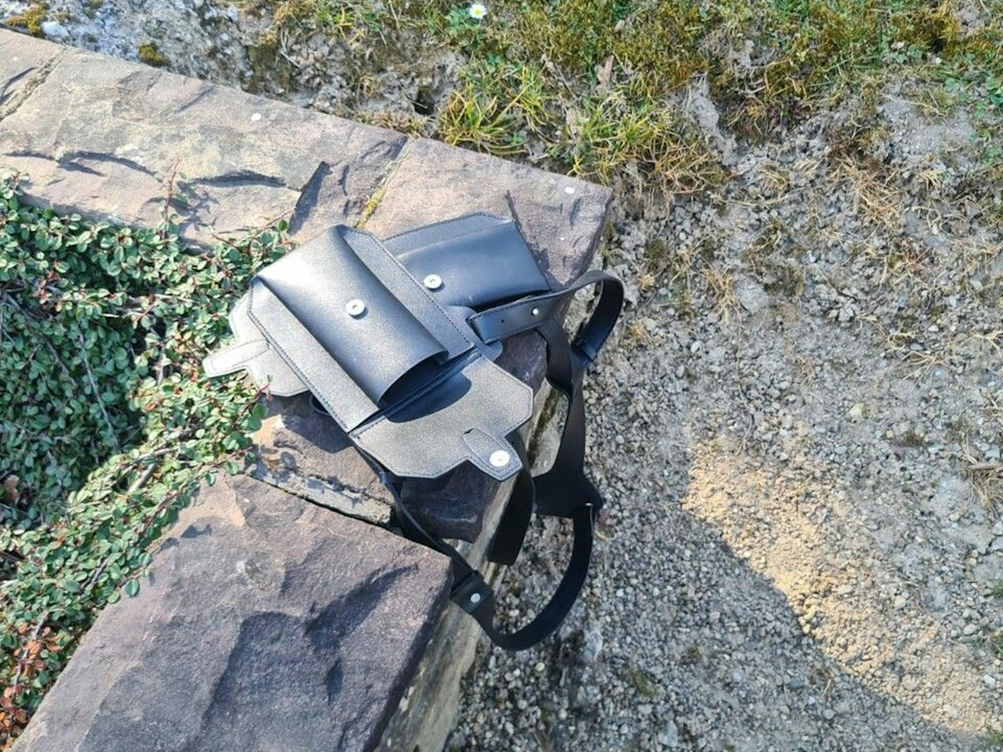 Ein Holster liegt auf der steinernen Umrandung eines Grabes.