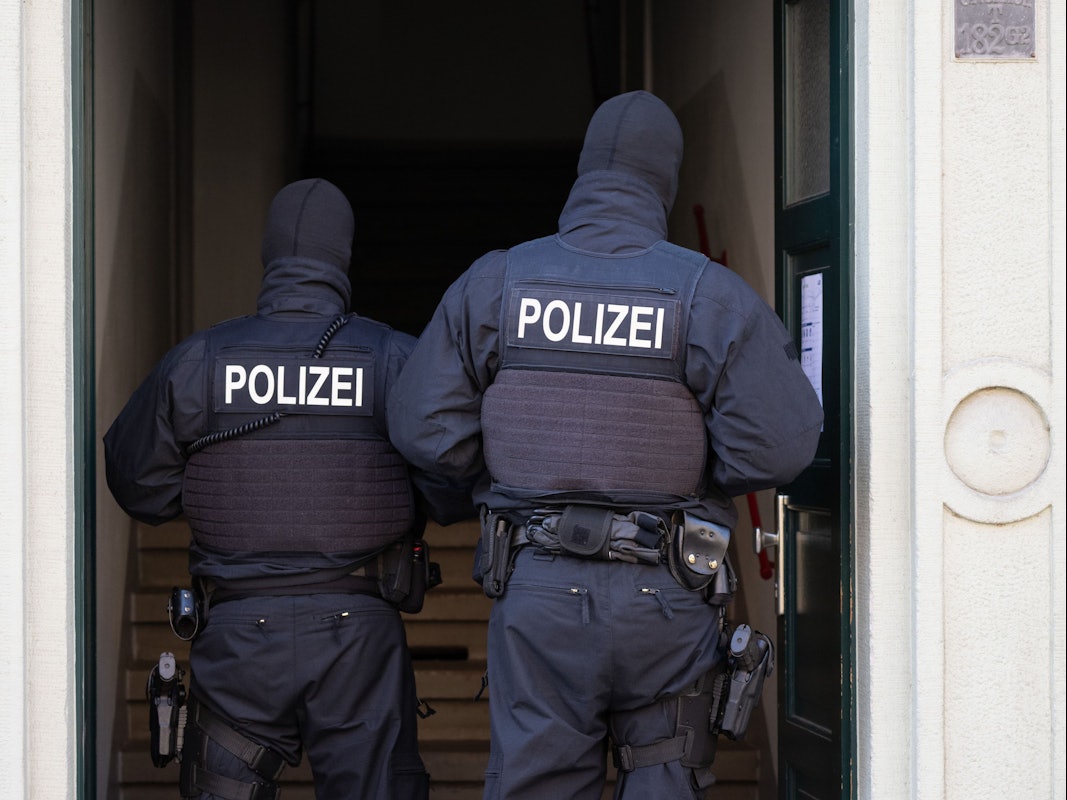 Das Foto zeigt Polizisten in einem Hauseingang bei einer Razzia.