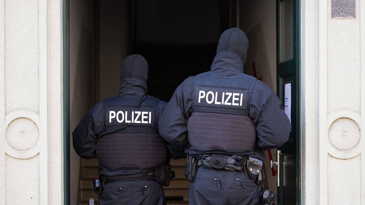 Das Foto zeigt Polizisten in einem Hauseingang bei einer Razzia.